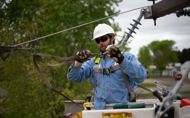 Técnico de una distribuidora eléctrica trabajando en una línea aérea