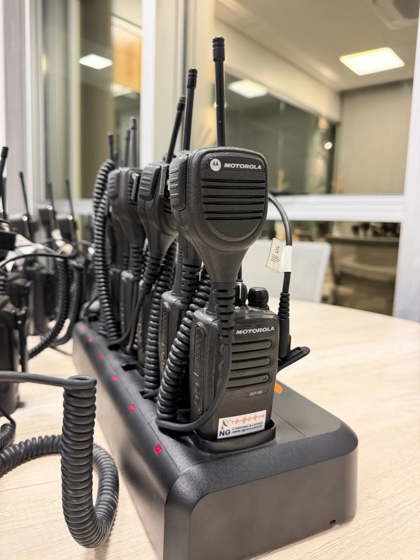 Radio portátil Motorola DEP450 en una base de carga, junto a otros equipos de la flota NG
